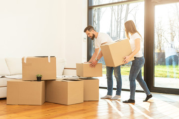 young couple moves to a new home. the family carries boxes of things after buying a home.