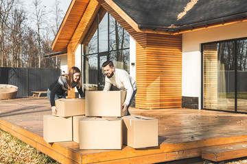 young couple moves to a new home. the family carries boxes of things after buying a home.
