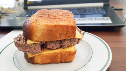 homemade cheese burger on desk in office with laptop background home work place