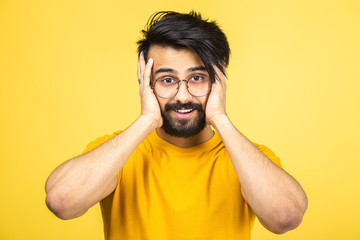Emotional portrait of a Hindu man in a yellow T-shirt on a bright orange background