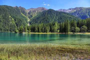 Anterselva Lake surrounded by red and yellow flowers, Trentino Alto Adige, Italy