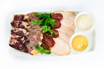 plate with a set of sausages and ham decorated with basil and sauce