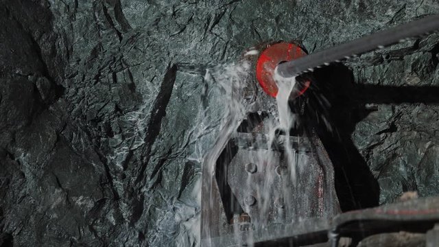 Rock surface drilling machine used to drill blast holes at mine tunnel, close up. Mining excavator drills a hole in the rock in copper pyrite mine. A large industrial drill boring into a rock wall.