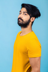 Emotional portrait of a Hindu man in a yellow T-shirt on a bright blue background