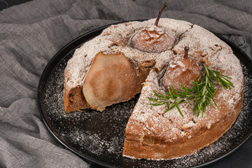 Delicious spice cake with pear, ginger and cinnamon on a dark kitchen counter.