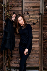 Full-length portrait. Photo in a stylish interior in the studio of a pretty glamorous brunette, a girl in a black T-shirt with long hair on a color alternative fashionable original background.