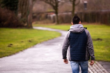 young man walking through neighborhood park