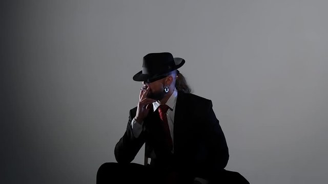Elegant man in a black hat is dancing an erotic dance. Spotlight on a black background. Close up, slow motion.