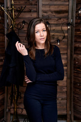Full-length portrait. Photo in a stylish interior in the studio of a pretty glamorous brunette, a girl in a black T-shirt with long hair on a color alternative fashionable original background.