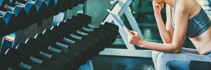 Fitness woman using tablet after exercise in gym