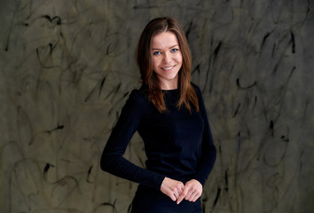 Photo of a pretty glamorous brunette girl in a black t-shirt with long hair on a gray alternative fashionable original background. Beauty concept, stylish portrait.