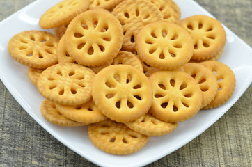 Delicious biscuit in white plate on wooden background