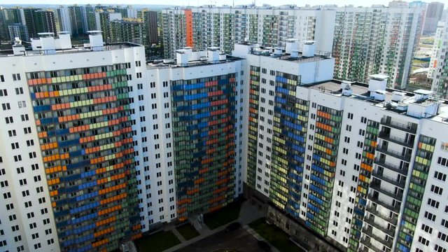 Flying over the residential houses with bright colorful facadesin a summertime. Motion. Aerial of the white buildings and inner yard with parked cars.