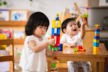 Asian boy and girl playing with colorful plastic blocks. Learning and imagination of young...