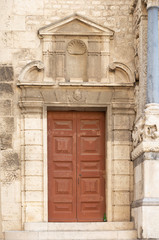 Brown front door with ornate stone carved facade and pillars