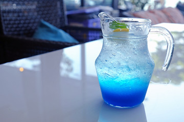Iced Italian blue soda served in a jug on white table
