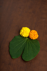 Indian Festival Dussehra, showing golden leaf (Bauhinia racemosa) and marigold flowers on a Brown...