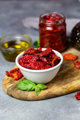 sun-dried tomatoes with basil and olive oil on a gray background