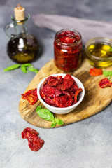 sun-dried tomatoes with basil and olive oil on a gray background