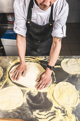 Professional chef cooking in the kitchen restaurant at the hotel, preparing dinner. A cook in an apron makes a salad of vegetables and pizza.