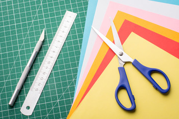 Photo of a scissors, ruler, scalpel and different colorful papers. Concept of making origami at home