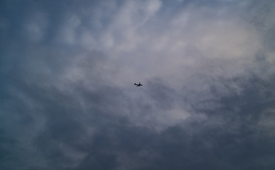 A Jet Flies High Above Beneath A Cloudy Sky
