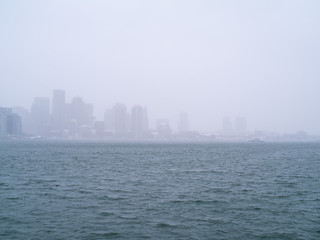 Naklejka premium Low Visibility of Boston City Skyline Over Water