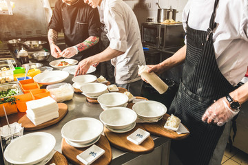 Professional chef cooking in the kitchen restaurant at the hotel, preparing dinner. A cook in an apron makes a salad of vegetables and pizza.