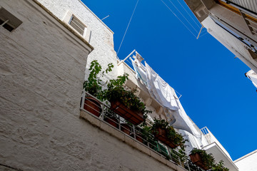 Scenic sight, street view from the beautiful town of Locorotondo, Bari province, Apulia, Puglia , Southern Italy. White laundry dries on white balcony