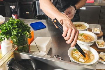 Professional chef cooking in the kitchen restaurant at the hotel, preparing dinner. A cook in an apron makes a salad of vegetables and pizza.