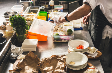 Professional chef cooking in the kitchen restaurant at the hotel, preparing dinner. A cook in an apron makes a salad of vegetables and pizza.