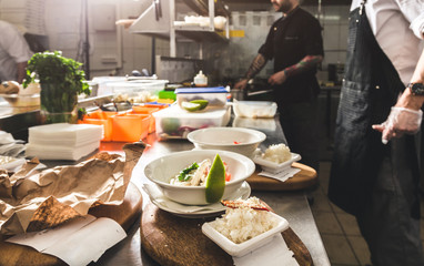 Professional chef cooking in the kitchen restaurant at the hotel, preparing dinner. A cook in an apron makes a salad of vegetables and pizza.