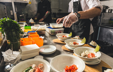 Professional chef cooking in the kitchen restaurant at the hotel, preparing dinner. A cook in an apron makes a salad of vegetables and pizza.
