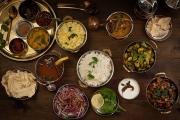 Variety of South Indian dishes on a wooden table served in traditional copperware