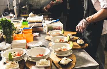 Professional chef cooking in the kitchen restaurant at the hotel, preparing dinner. A cook in an apron makes a salad of vegetables and pizza.