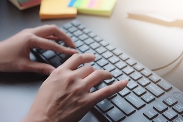 2 hands of Asian woman is press, typing on 2 language keyboard as Thai and English. Maybe preparation about information to report, chat to lover or shopping online by connect to internet at home, cafe