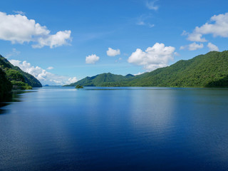 View from Vachiralongkorn Dam, Kanchanaburi, Thailand. Water and the blue sky in the background is a green mountain.