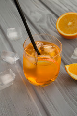 Aperol spritz cocktail in the glass on the grey wooden background. Location vertical. Closeup.