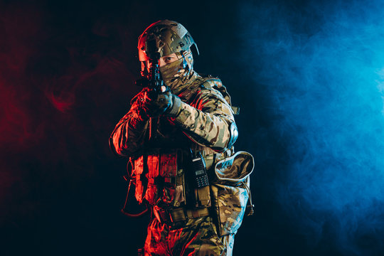 Portrait Of Young Military Man Pointing Gun, Wearing Green Army Wear, Camouflage Isolated Over Ultra-violet Background