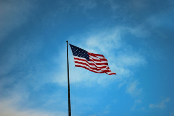 Waving flag of the United States in front of a cloudy blue sky