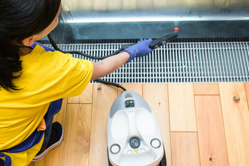professional cleaning service. woman in uniform and gloves sponge washes panoramic windows in the cottage. washing steam mop and scraper