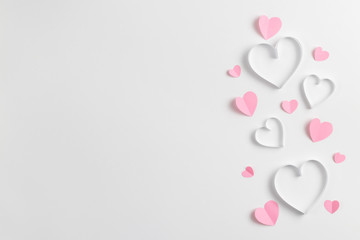Composition for Valentine's Day February 14th. Delicate composition of pink hearts made of paper on a white background. Heart cut out of paper. Greeting card. Flat lay, top view, copy space.