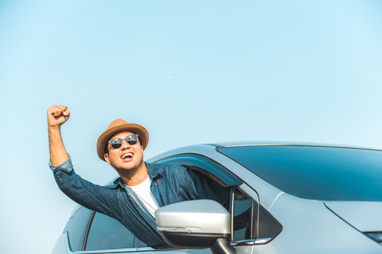 Young handsome asian man driving car to travel on his holiday vacation time with beautiful blue sky.