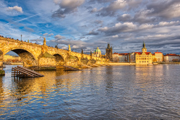 Beautifully illuminated Charles Bridge at sunset with surrounding buildings, Prague
