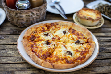 Slice of delicious pizza On a plate on a wooden table