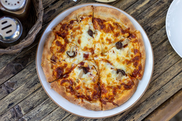 Slice of delicious pizza On a plate on a wooden table