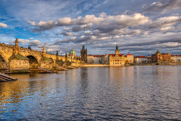 Beautifully illuminated Charles Bridge at sunset with surrounding buildings, Prague
