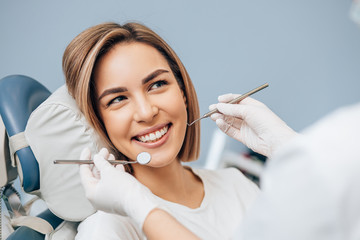 portrait of young blond good-looking woman on dental examination, treating teeth in professional...