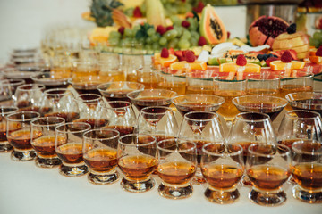 Catering table with alcoholic and non-alcoholic drinks, dishes and snacks food on the event. Service at business meeting, party, weddings. Selective focus, space for text.