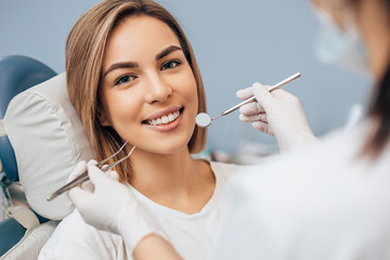 portrait of young caucasian woman with perfect smile in dental office, come to treat spoiled teeth, look at camera